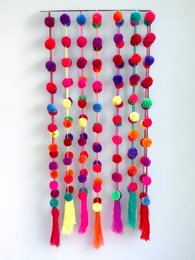 Colorful pom-pom garland with vibrant red, purple, and orange pom-poms hanging from a string.