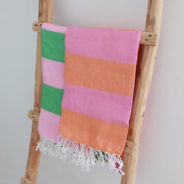  Hammam towel in vibrant orange and pink colors, with a striped pattern and fringed edges.