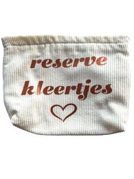  A white fabric organizer bag with the text "reserve kleertjes" (reserve clothes) and a heart symbol printed on it. The bag appears to be made of a soft, textured material and is placed on a woven straw mat.