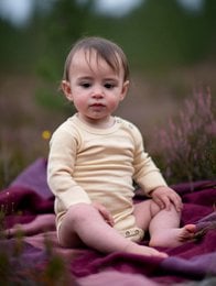 Soft, natural-colored merino wool baby romper with long sleeves. Suitable for newborns and infants.