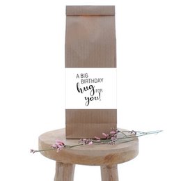A birthday-themed tea package with a cardboard box and a "Birthday Hug" message printed on it. The package contains tea bags and other decorative elements.