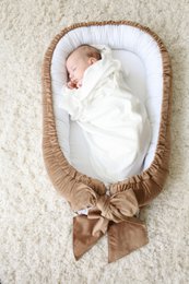 Soft, plush velvet babynest in a variety of colors including mint, light gray, beige, pearl, and dirty pink. Features a decorative bow detail. Ideal for newborn sleep and comfort.