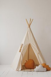 Beige teepee tent for kids' play area, made of cotton fabric with wooden poles, suitable for indoor or outdoor use.