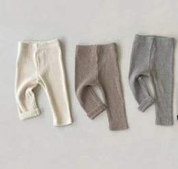 Organic cotton kids' leggings in neutral colors of brown, gray, and cream-white, available in sizes from 3-6 months to 2-3 years.