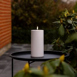 Tall, cylindrical white pillar candle for outdoor use, made of LED light for safe and long-lasting illumination.