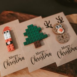 Set of 3 Lego-style Christmas cards with festive designs including a Christmas tree, reindeer, and Santa Claus. The cards feature colorful, whimsical elements made from Lego-like bricks.