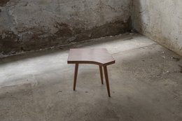 Wooden side table with curved legs and a rectangular top in a rustic, minimalist design.