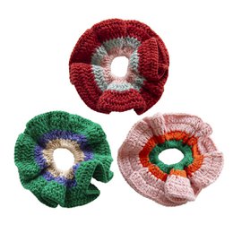 Assorted crochet hair scrunchies in red, green, and pink colors with floral designs.