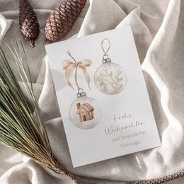 A6 greeting card with Christmas-themed illustrations, including a glass ornament, a pine cone, and a small house. The card is printed on textured paper and comes with or without a kraft paper envelope.