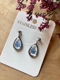 Stainless steel drop earrings with teardrop-shaped blue stones resembling forget-me-not flowers.