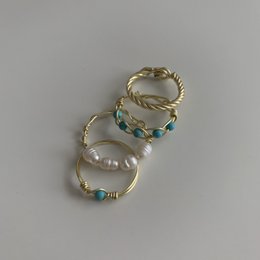 Turquoise stone ring with twisted gold and silver bands, featuring various gemstone accents including pearls.