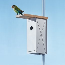 A white and black birdhouse with a perch for birds to rest on. The birdhouse has a simple, modern design and is suitable for outdoor use.