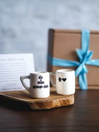  Two ceramic mugs with paw print and "I love my dog" text on a wooden board, accompanied by a handwritten note.