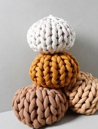 Soft, chunky knit pillow cover in Braun, Weiß, and Senf colors. Plush, textured design with a round, spherical shape.