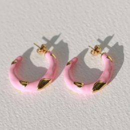  Bold pink statement earrings with a curved, hoop-like shape.