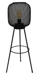 A tall, black metal floor lamp with a round, woven mesh shade that provides a warm, ambient lighting effect.