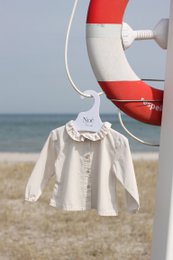 Soft, cotton baby shirt in off-white color with ruffled collar and short sleeves. Suitable for casual wear or special occasions.