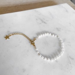 Elegant gold and white bracelet with a star charm, featuring a delicate chain and pearl-like beads. Suitable for casual or formal wear.