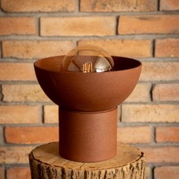 A modern, natural red clay table lamp with a round, bowl-shaped design and a warm, glowing light.