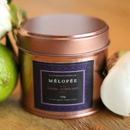 A round, tall candle with a peony and lemon scent, presented in a copper-colored tin.
