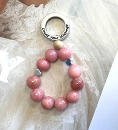 Rhodochrosite keychain with pink gemstone beads, featuring a love charm.