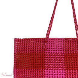  Colorful woven tote bag with a mix of red, pink, purple, orange, green, and blue hues. The bag has a rectangular shape and features a large open compartment for storage.