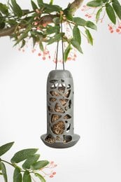 A round, tall bird feeder made of 100% recycled plastic with a decorative cutout design. Suitable for holding bird seed or suet.