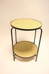 Round side table with woven webbing top and bottom shelf in a modern, minimalist design.