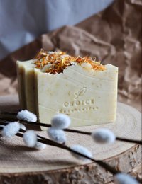 Natural, vegan soap bar with coconut milk and calendula. Rectangular shape with visible pieces of calendula flowers on the surface.