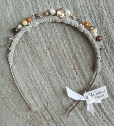 A delicate floral headband with a variety of colors and textures, including white, pink, and natural blonde beads or flowers. The headband has a ribbon or bow accent.
