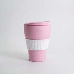  A foldable, reusable coffee cup made of durable silicone material in a soft pink color. The cup features a textured grip and a snap-on lid for easy transport.