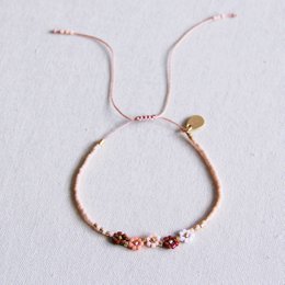 Delicate bracelet with 5 mini daisy flowers in a mix of nude colors, perfect for adding a touch of nature-inspired style to any outfit.