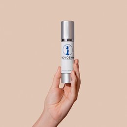 Moisturizing cream in a silver bottle with a blue logo. The cream is being held in a person's hands.