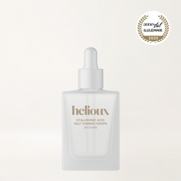 Hyaluronic acid self-tanning drops in a clear glass bottle with a white dropper. The bottle is packaged in a white and gold box.
