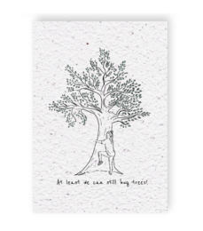 A hand-drawn illustration of a tree with the text "At least we can still hug trees" written below it. The image appears to be a greeting card or wall art with a simple, minimalist design.