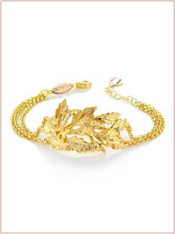  Gold and burnished leaf-shaped cuff bracelet with intricate detailing.