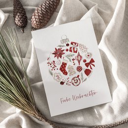 A6 greeting card with a festive design featuring Christmas symbols like pine cones, snowflakes, and a red heart. The card is printed on textured paper and available with or without a kraft paper envelope.