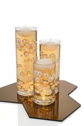  Golden pearl floating candles, tall cylindrical glass containers, warm amber light, elegant dinner table decor, luxury ambiance