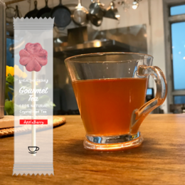  The product is a pack of 30 AppleBerry Tea Tea-Pop Sticks, which are tea-flavored popsicles without packaging or trays. The image shows a box containing the sticks and a single stick in a glass mug. The tea-pop sticks have a red, flower-shaped design.