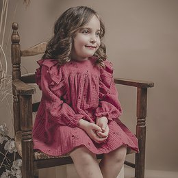 A pink, ruffled dress with long sleeves and a flared skirt. The dress has a feminine, vintage-inspired style.
