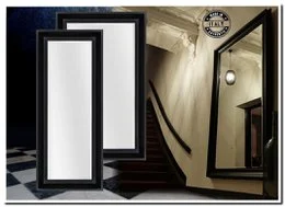 A large, rectangular black framed mirror with a sleek, modern design. The mirror is mounted on a black console table, creating a stylish and minimalist entryway or hallway display.