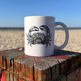 A white ceramic mug featuring a detailed illustration of a starfish against a blue background, surrounded by seashells and other beach elements.