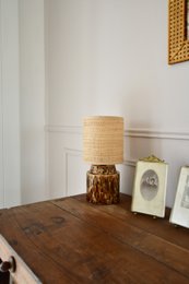  Tall, cylindrical ceramic lamp with a raffia shade and a textured, brown and blue base.