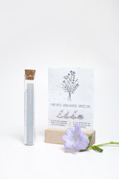 Wildflower seeds in a growing paper container, with a purple flower and a label that says "100 Moments of Happiness - Cheer up... #field flowers".