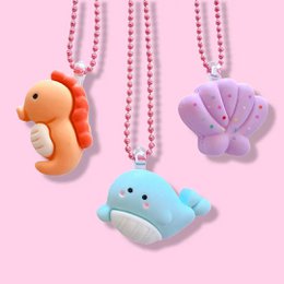 Colorful plush sea creature necklaces in the shapes of a seahorse, whale, and starfish. The necklaces feature pastel colors and are attached to a pink beaded chain.