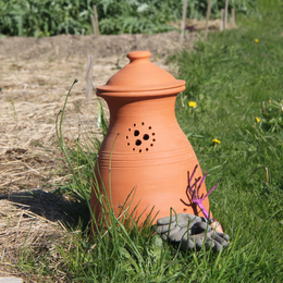 A terracotta compost bin with a domed lid, designed for composting organic waste in a garden or outdoor setting. The bin features ventilation holes and a rustic, earthy appearance.