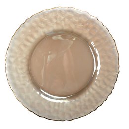  A round, textured gold-colored trivet or plate with a raised pattern on the surface.