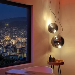 A round, glass pendant light with a metallic finish, available in various sizes and color combinations including gold/clear, chrome/clear, black/smoke, and suitable for use in pendant lighting applications.