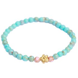'Turquoise stone flower gold bracelet with beaded details and charms. Includes colors, materials, style, and shape details to enable semantic search.'
The bracelet features turquoise-colored beads with a gold-tone flower charm. The bracelet has a delicate, feminine style with a mix of materials including stone and metal. The round, beaded shape creates a simple, elegant look.