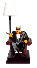  A black metal desk lamp with a white lampshade. The lamp base features a figurine of a wolf wearing a suit and sitting in a chair.